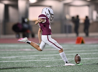 Young athletic tackle football player kicking a field goal during a game