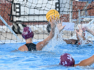 Young teen girls playing a competitive game of waterpolo