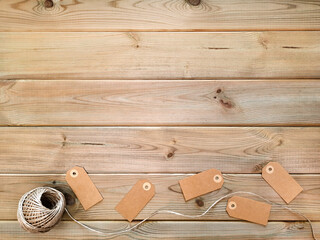 Blank gift tags and roll of thread at bottom on rustic background. Flat lay. Gift wrapping set made from natural materials. Threads and address tags made from recycled paper.
