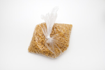Italian durum wheat pasta in a plastic bag on a white background, food supplies, Italian traditions.