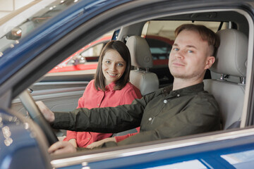 man and a woman couple in a car dealership buy or trade in. car rental or repair service. happy and successful married couple choose a new car on credit. happy two people holding keys and laughing