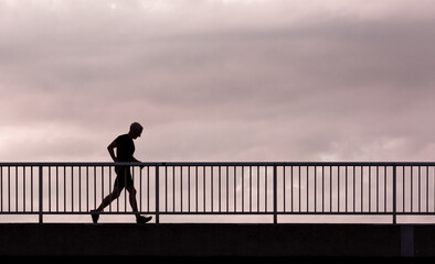 silhouette of a person walking on a bridge