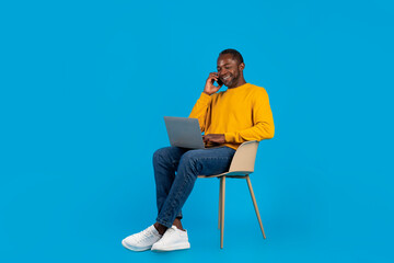 African american man freelancer working on laptop, having phone call