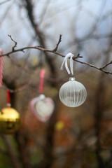 Bare tree in the garden, decorated with colorful Christmas ornaments. Selective focus.