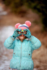 Smiling child outdoors birdwatching in winter with coat, hat and binoculars