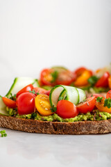 Tasty open sandwich from toasted sourdough bread with mashed avocado and fresh tomatoes