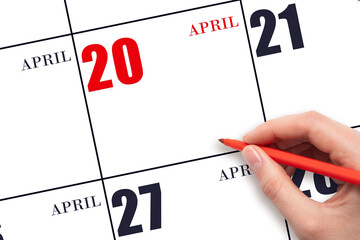 A hand holding a red pen and pointing on the calendar date April 20. Red calendar date, copy space,...