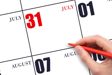 A hand holding a red pen and pointing on the calendar date July 31. Red calendar date, copy space,...