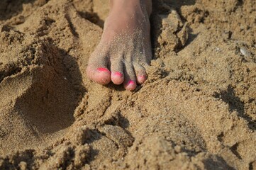 A young woman's foot covered with fine sand on the beach