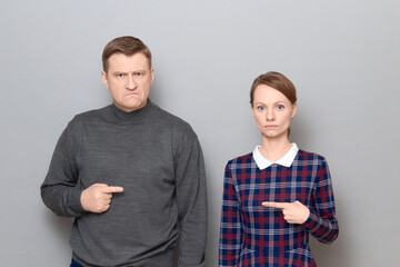 Man and woman pointing at each other, with different face expressions