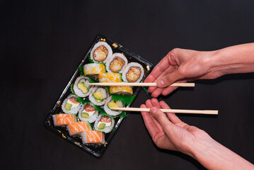 delicate hands with chopsticks and assorted sushi platter