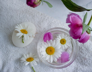 Cosmetic soap, chamomile flower, peony on a light background