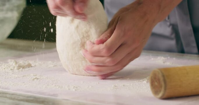 Extreme close-up shot of hands of female chef kneading flour dough for pizza