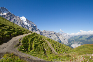 Mountain path in Swiss Alps with snow covered mountains in the back