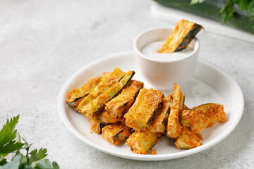 Zucchini sticks baked with cheese, herbs, breadcrumbs and cream yogurt sauce. Roasted Zucchini snack.