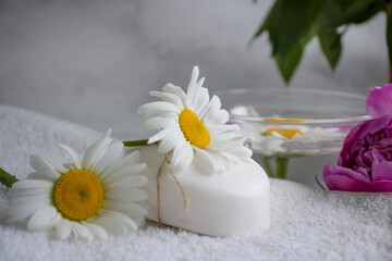 Fototapeta na wymiar Cosmetic soap, chamomile flower, peony on a light background