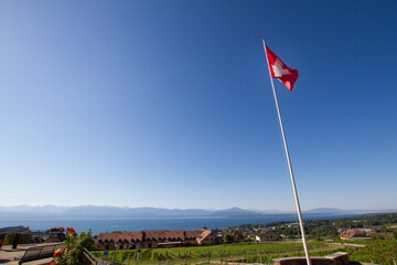 Switzerland flag above lake Geneva and vineyards
