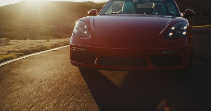 Epic sunset drive, red sports car driving on desert road at sunset