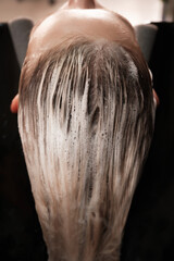 Young woman in a hairdressing salon dyes her hair blond and washing head