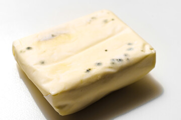 a pack of spoiled butter with mold on a white background. 