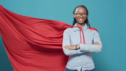 African american woman posing as superhero with red flying cape, wearing cartoon comic costume with...