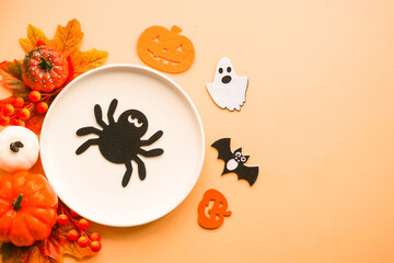 Halloween food concept. White plate, cobweb, hands, spiders, pumpkins. Flat lay image with copy space.