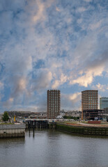 Obraz premium Antwerpen, Flanders, Belgium - July 10, 2022: Jattendijk lock entrance from Scheldt River. 2 of 5 modern condominium builidngs on Bataviastraat under sunrise blue cloudscape.