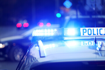 Radiowóz polska policja z  Sygnalizator błyskowy niebieski na dachu radiowozu.  Alarmowo wieczorem.  - obrazy, fototapety, plakaty