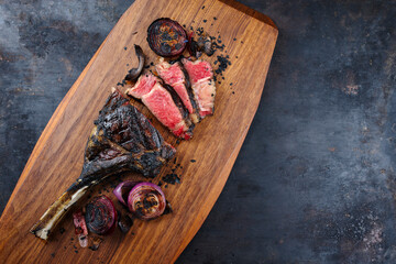 Traditional barbecue dry aged Kobe tomahawk steak with grilled onions served as top view on a...