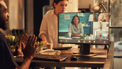 Male employee talking to colleagues on online conference with webcam, attending business teleconference meeting at sunset. Using remote videoconference call on internet connection at job.
