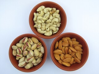 Almonds, pistachios, and Cashew in bowls on white background 