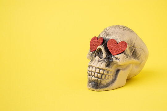 Skull with red hearts against a yellow background. Halloween love and romantic concept.