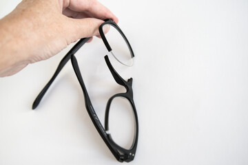 Unrecognizable human hand holding broken glasses frame.