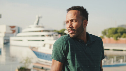 Young man enjoys relaxing while sitting in the harbor with yachts on the background