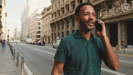 Young man talking on mobile phone while standing on the street next to the road