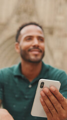 Close up, young man uses cellphone while sitting on the steps of the Sagrada Familia in Barcelona
