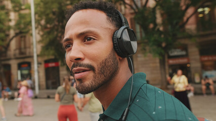 Young man tourist walks around the square of the old city, listens to music in headphones.