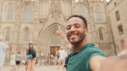 Close-up of young man tourist with backpack on his shoulder taking selfie on the Sagrada Família...
