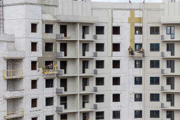 The process of insulating external walls in a multi-storey building under construction.