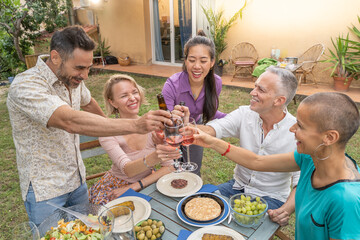 Group of multiracial friends toasting with beautiful smile around the table at house patio diner.