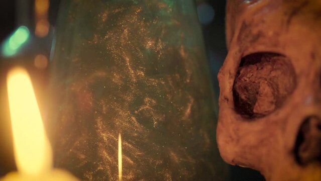macro of magic potion and skull lit by candle