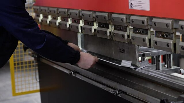 A worker bends a part on a sheet bending machine. Shooting in industrial production