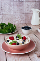 cottage cheese in a bowl with fresh berries on a wooden table