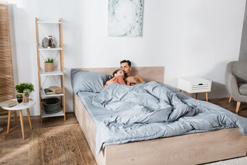 Fototapeta premium young couple in love holding hands while sleeping under grey blanket in modern bedroom.