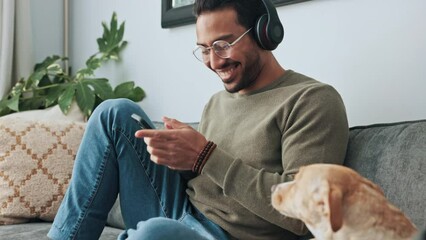 Man, phone and headphones on sofa with dog listening to music, podcast or online social media. Living room, relax and happy owner bonding with pet on couch, audio or radio streaming on mobile at home