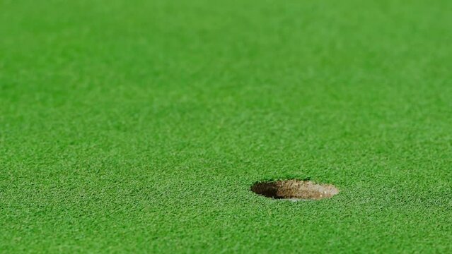 A golf ball after being hit by a club flies across the lawn into the hole
