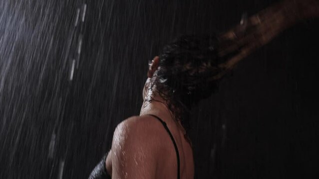 Hot woman dancer in black underwear shaking her head and long hair under the rain