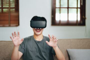 portrait of a young Asian man using virtual reality simulator headset at home