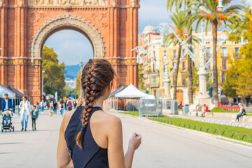 Back view of a beautiful young lady with braided hair in front of The Arc de Triomf in Barcelona....