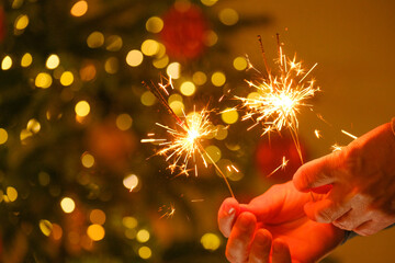 Christmas party. Sparkling bengal fire in the hands. Holiday traditions. Bengal lights on glowing...